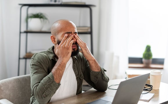 Man rubbing eyes because of dry eye symptoms