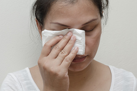 Woman holding a cloth to her eye because of an injury