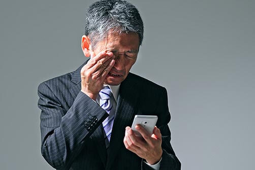 Man on cell phone experiencing eye pain from glaucoma symptoms